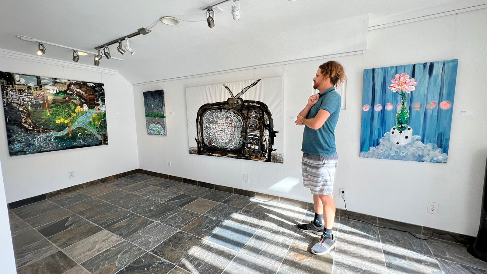 A man standing in a room looking at a painting