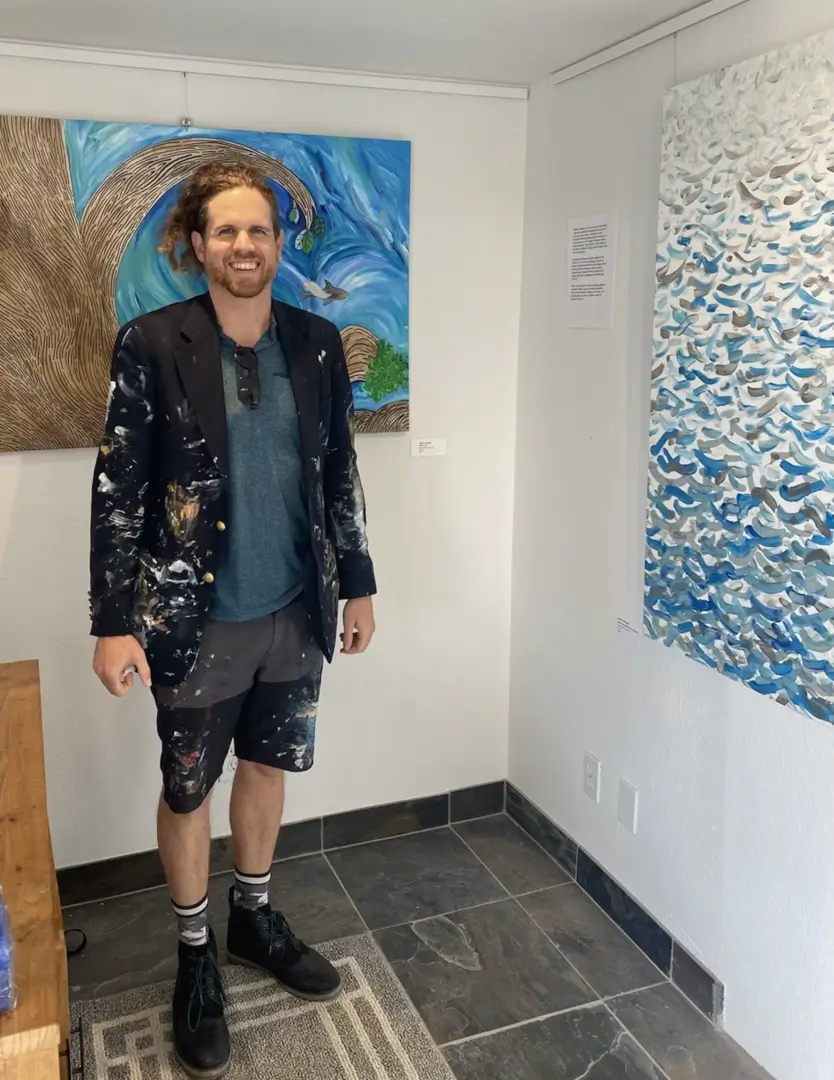 Painter in half pant and coat standing near paintings